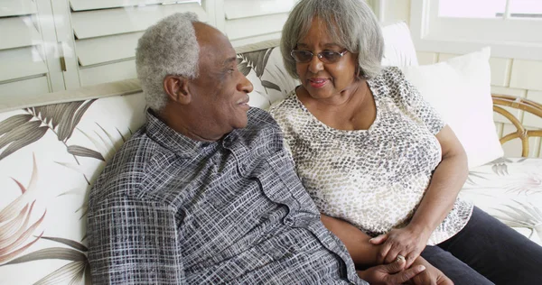 Happy retired black couple sitting on a couch