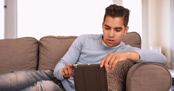 Jovem Hispânico Homem Sentado Sofá Usando Tablet Computador Sala Estar — Fotografia de Stock