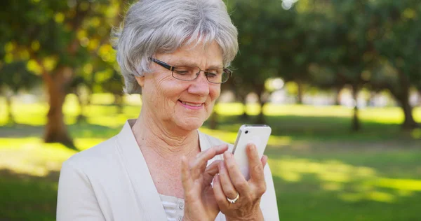 Senior Kvinne Tekster Smarttelefon Parken – stockfoto