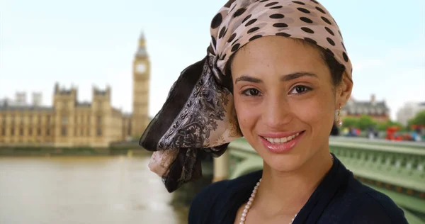 Close up of cute Latina woman in stylish headscarf smiling near Big Ben