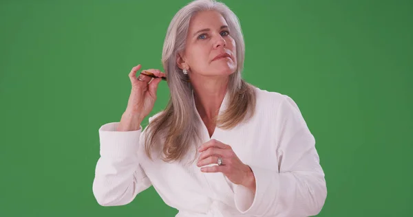 高级白种人妇女在绿屏上梳理健康头发的肖像 — 图库照片