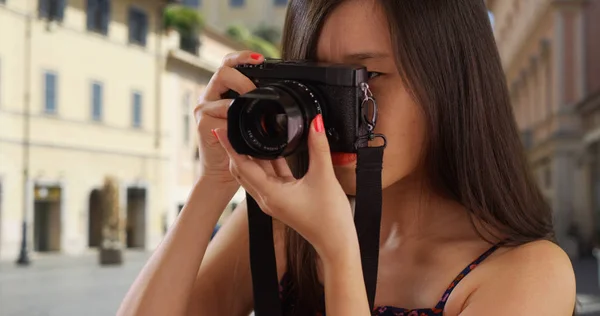 Close up of Asian millennial photographer taking photos with camera in Europe