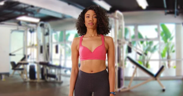 Frontal shot of attractive African-American fitness female standing inside gym