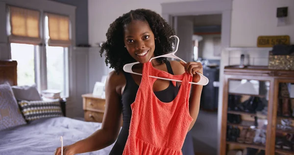 Portrait of attractive black woman deciding what dress to wear