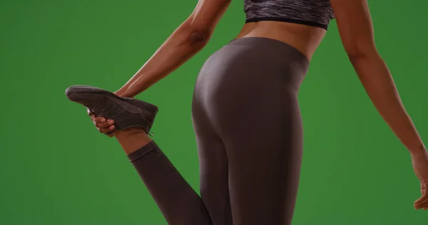 Healthy athletic black woman stretching before exercising on green screen