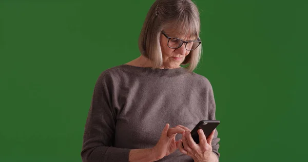 古い白人女性が緑色の画面でテキスト メッセージを送信する携帯電話 — ストック写真