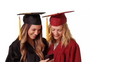 İki genç kadın üniversite grads Smartphone birlikte kullanarak arka plan beyaz