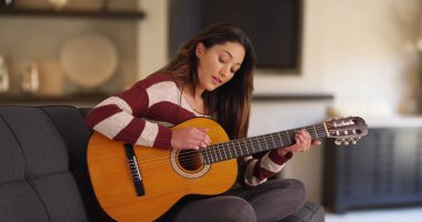 Sevimli Latina kadın ev gitar çalıyor ve şarkı uzanmanız portresi