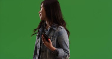 Denim ceket telefon yeşil ekranda müzik dinlemek hip Asyalı kadın