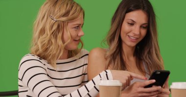 İki beyaz erkek arkadaş mobil cihaz üzerinde yeşil ekran kafede oturan paylaşımı