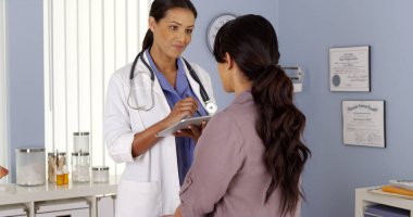 Black Primary Care Physician talking to female patient in Exam room clipart
