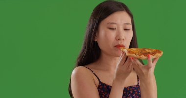 Yeşil ekranda dilim pizza yeme genç Çinli kadın portresi