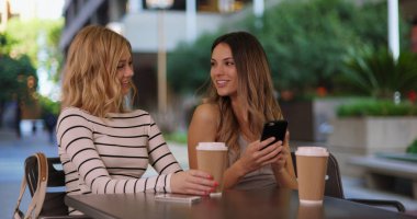 Mutlu kız telefonu kullanarak kafeterya masada oturan birkaç portresi