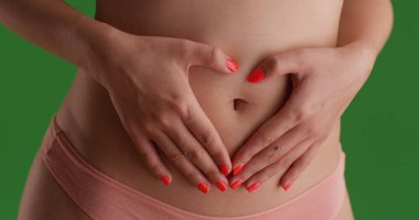 Mide üstünde yeşil perde ile sağlıklı dişinin midsection closeup eller