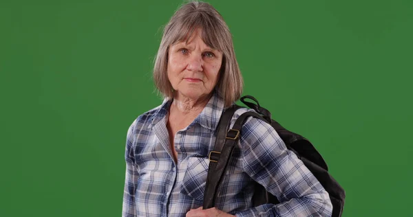 船尾白人女性が緑色の画面上のバックパックに立ってポーズを成熟します — ストック写真