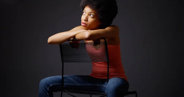 非洲女人不经意地坐着双臂在椅子后面 — 图库照片