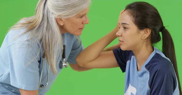 Concussed soccer player is consoled by the team medic on green screen