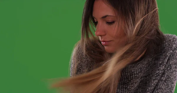 Close up of beautiful millennial woman with hair blowing in wind on greenscreen