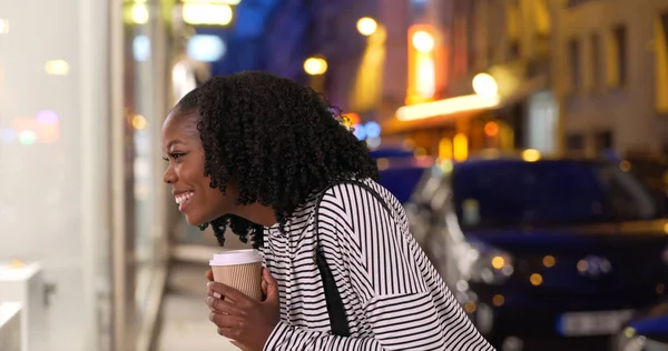 Niedlich Lächelnde Frau Trinkt Kaffee Und Schaut Abends Auf Schaufenster — Stockfoto