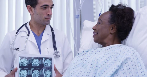 迷人的拉丁医生在平板电脑上显示女性患者的大脑扫描 — 图库照片