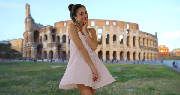 Beautiful Latina woman in white sundress posing near Roman colosseum