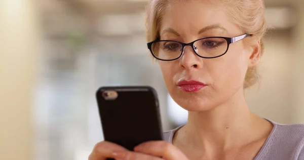 職場でスマート フォンで成功した女性着用メガネ テキスト メッセージのクローズ アップ — ストック写真