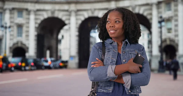 Black female traveling in London poses in front of landmark smiling