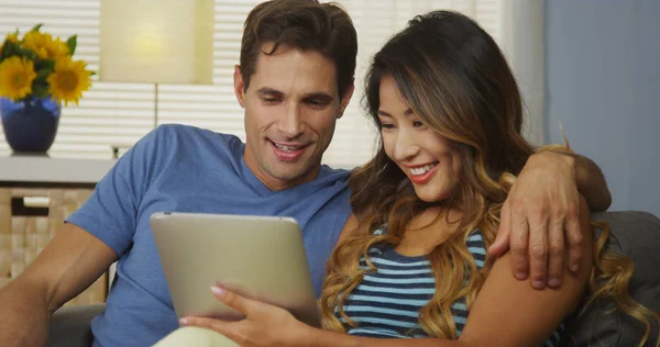 幸福的异族夫妇一起使用平板电脑在沙发上 — 图库照片