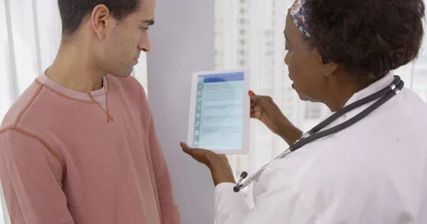 Senior African Zeigt Männlichen Latino Patienten Verschiedene Gesundheitspläne Auf Tablet — Stockfoto