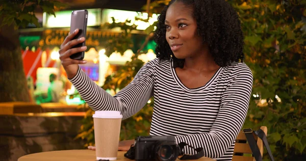 可爱的黑人女子晚上在食品摊附近拿着智能手机自拍自拍 — 图库照片