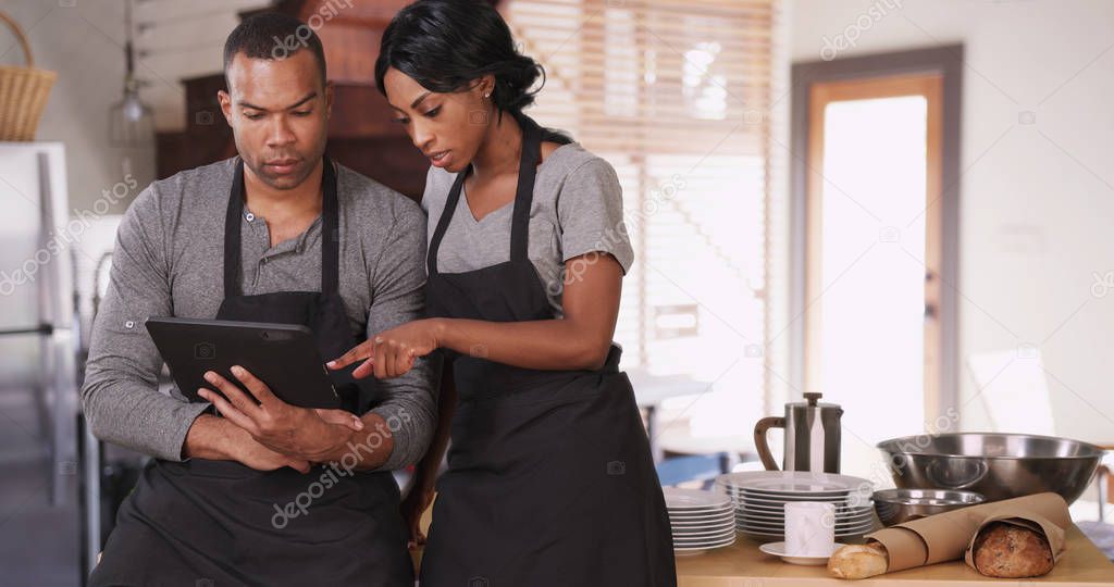 Small business owner showing employee new plan on tablet computer