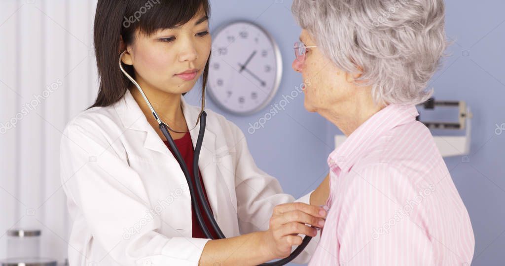 Chinese doctor listening to elderly patient's heart