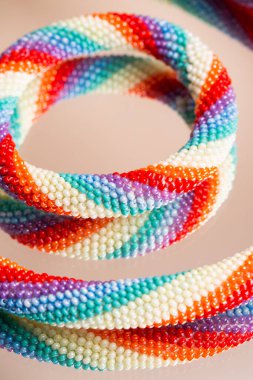 Boncuklu bir bileziğin renkli dokuması. Cam masaya yansıyan yansıma. Kapat..