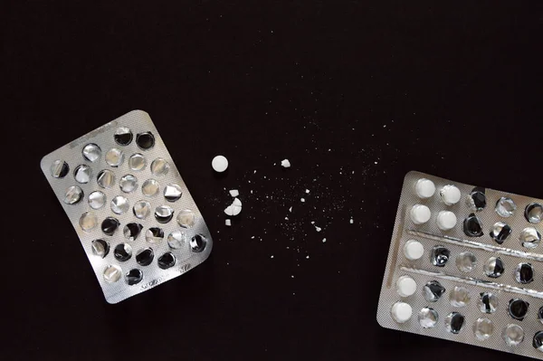 Siyah arka planda beyaz ezilmiş tablet hapları. İlaçlar bir bütün olarak ve kabarcıklar başladı. Siyah arka planda su toplayan haplar. Sağlık konsepti, farmakoloji ve uyuşturucular.