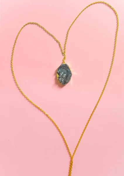 Pembe arka planda izole edilmiş jeotlu altın kolye. El yapımı aksesuarlar. Üst Manzara. Seçici odak.