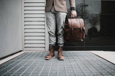 Elinde çok pahalı deri bir çanta tutan bir adam.