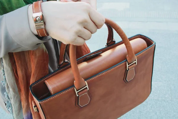 Elinde çok pahalı deri bir çanta tutan bir adam.