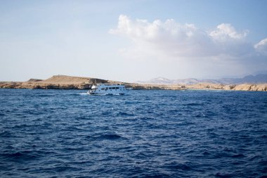 Denizde kayaların arkasında küçük bir tekne.