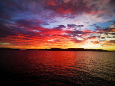 Adaların üzerinde gün batımının çarpıcı yansıması ön planda.