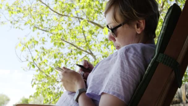 Menina artista em óculos de sol desenha esboços em notebook — Vídeo de Stock