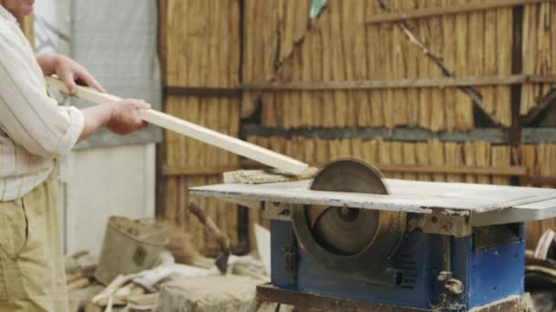 Hombre mayor aserrando madera en la máquina con una sierra circular — Vídeo de stock
