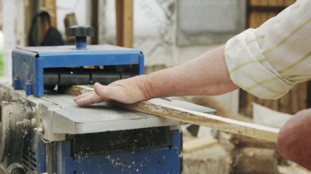 Ηλικιωμένος άνδρας ξυλουργός χτίζει μια μικρή βάρκα με τα χέρια του από το ξύλο σε ένα μικρό εργαστήριο — Αρχείο Βίντεο