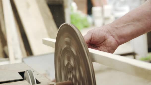 Ein älterer Tischler baut in einer kleinen Werkstatt mit seinen Händen aus Holz ein kleines Boot — Stockvideo