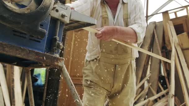 Anciano carpintero construye un pequeño barco con las manos de madera en un pequeño taller — Vídeo de stock