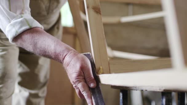 Homme âgé charpentier construit un petit bateau avec ses mains en bois dans un petit atelier — Video