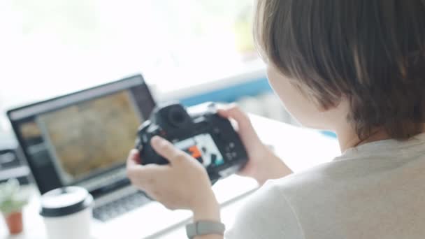 Fotógrafa revisando fotos en su cámara en casa — Vídeos de Stock