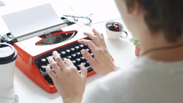 Женщина вручную печатает на красной винтажной пишущей машинке — стоковое видео