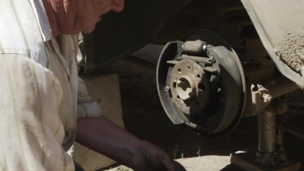 Hombre mayor dedicado a la reparación de un coche viejo — Vídeos de Stock