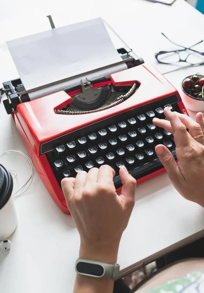 Mulher mão trabalhando com vermelho brilhante máquina de escrever vintage — Fotografia de Stock
