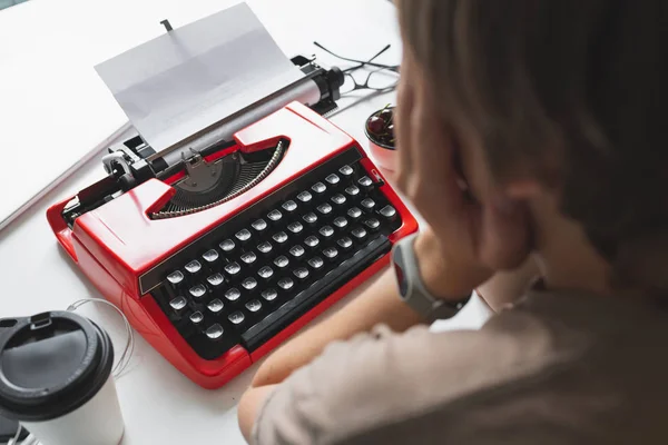 Femme écrivain réfléchie travaillant sur un livre sur sa machine à écrire bureau rouge — Photo